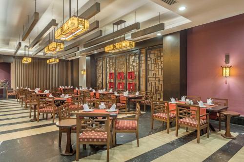 a dining room with tables and chairs and chandeliers at Kirman Belazur Resort & Spa in Belek