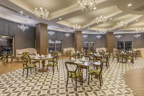 a dining room with tables and chairs and chandeliers at Kirman Belazur Resort & Spa in Belek