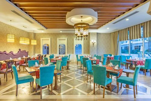 a dining room with tables and chairs and a chandelier at Kirman Belazur Resort & Spa in Belek