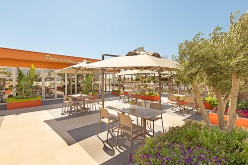 an outdoor patio with tables and chairs and umbrellas at Kirman Belazur Resort & Spa in Belek