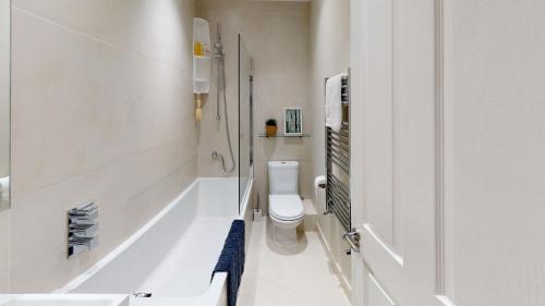 a white bathroom with a toilet and a bath tub at Madison Hill - White Hill House 3 - 1 bedroom flat in London