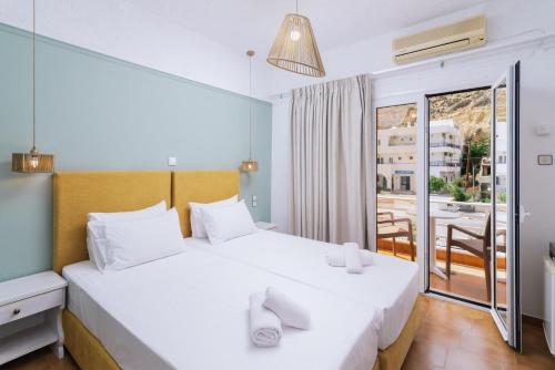 a bedroom with a bed and a balcony at Elea Terra Hotel in Matala