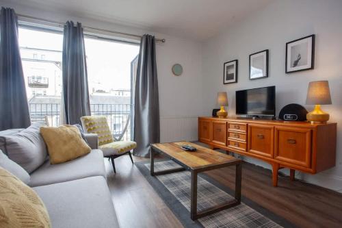 a living room with a couch and a tv at Stylish 3rd Floor Flat in Historic Merchant City in Glasgow
