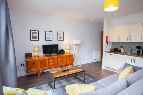 a living room with a couch and a tv and a table at Stylish 3rd Floor Flat in Historic Merchant City in Glasgow