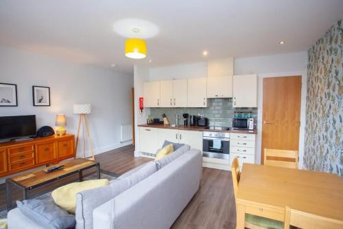 a living room with a couch and a kitchen at Stylish 3rd Floor Flat in Historic Merchant City in Glasgow