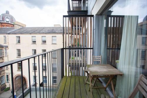 a balcony with a wooden table and a wooden bench at Stylish 3rd Floor Flat in Historic Merchant City in Glasgow