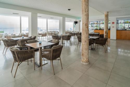 a dining room with tables and chairs and windows at Hotel Amic Horizonte in Palma de Mallorca