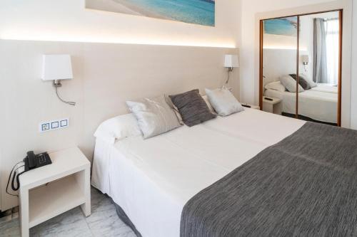 a bedroom with a large white bed and a mirror at Hotel Amic Horizonte in Palma de Mallorca