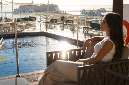 a woman sitting on a bench next to a swimming pool at Hotel Amic Horizonte in Palma de Mallorca
