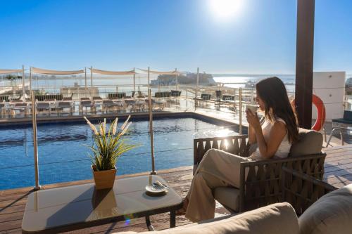 a woman sitting on a bench looking at her cell phone at Hotel Amic Horizonte in Palma de Mallorca
