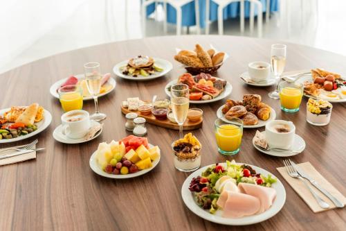 a table with plates of breakfast foods and glasses of orange juice at Hotel Amic Horizonte in Palma de Mallorca