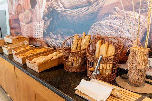 a counter with baskets of bread and baskets of pastries at Hotel Amic Horizonte in Palma de Mallorca