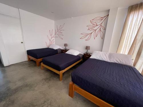 two beds in a room with blue sheets at Killamoon House Paracas in Paracas