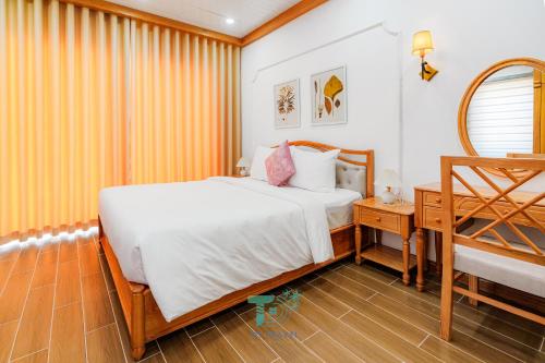 a bedroom with a bed and a table and a mirror at DT Retreat - Biệt thự nguyên căn - 3 Phòng ngủ - Novaworld Phan Thiết in Phan Thiet