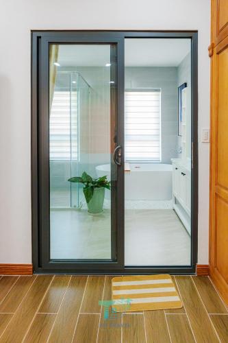 a bathroom with a sliding glass door with a plant at DT Retreat - Biệt thự nguyên căn - 3 Phòng ngủ - Novaworld Phan Thiết in Phan Thiet