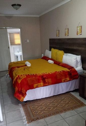 a bedroom with a large bed with a yellow blanket at Courtlyguesthouse in Witbank