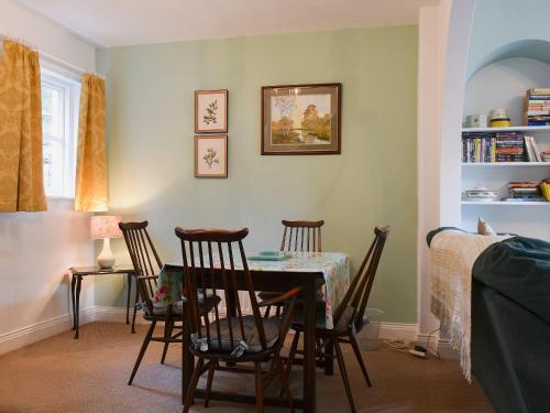 une salle à manger avec une table et quatre chaises dans l'établissement Poachers Cottage, à Keswick