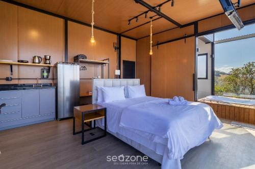 a bedroom with a large white bed and a kitchen at Cabana romântica com vista na serra VST037 in São Paulo dos Pinhais