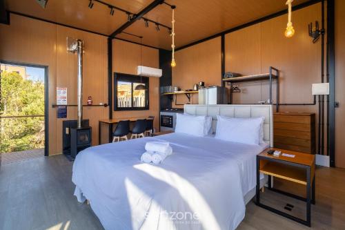 a bedroom with a large white bed and a kitchen at Cabana romântica com vista na serra VST037 in São Paulo dos Pinhais