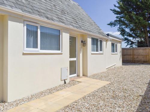 a white house with a door and a gravel driveway at Stars Cottage in Moreton