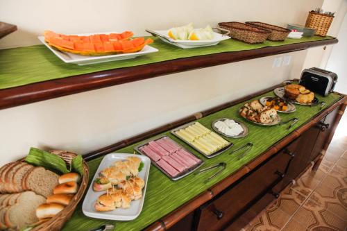 a buffet with different types of food on a table at Pousada Canto da Praça in Bertioga