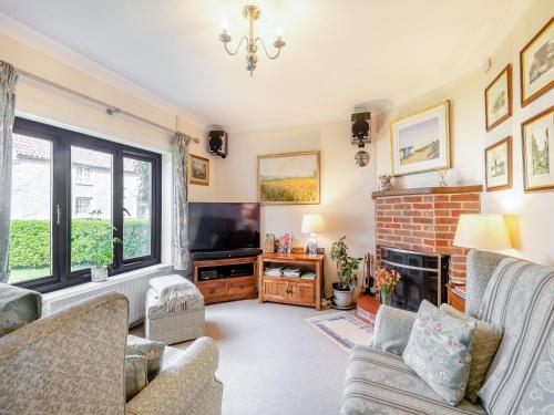 a living room with a fireplace and a tv at Langford Cottage in Ringstead