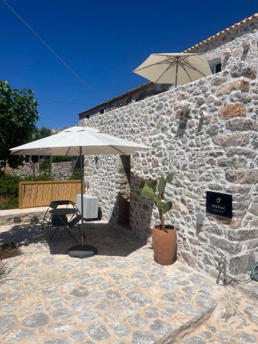 a stone building with a table and an umbrella at Σουίτα ΣΙΚΛΟΣ στο Καραβοστάσι Ν Οιτύλου Μάνης in Karavostasion