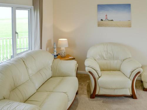 a living room with two white chairs and a couch at Roses Place in Bacton