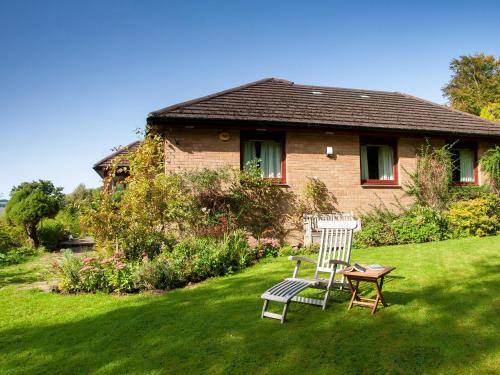 a house with two chairs and a table in the yard at Rosmuire in Rhu