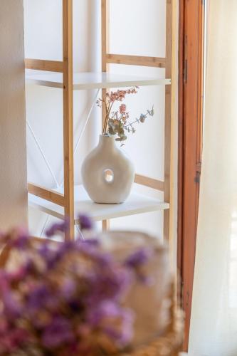 a white vase sitting on a shelf with flowers at Filoxenia Apartments in Mytilini