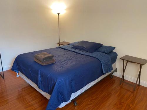 a bed in a room with a blue blanket and a table at Westminster Cozy Rooms in Westminster