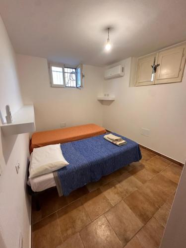 a small room with a bed with a blue blanket at Tentadore in La Caletta