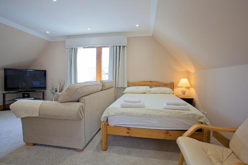 a bedroom with a bed and a couch and a television at Glengyle Guest House in Fort William