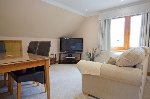 a living room with a couch and a desk and a tv at Glengyle Guest House in Fort William