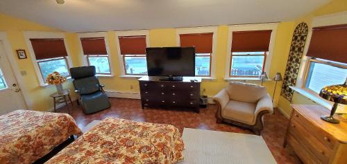 a bedroom with a bed and a tv and a chair at Simmons Motel and Suites in Hershey