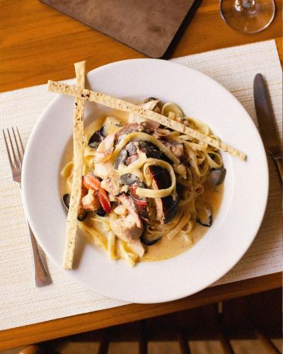 a plate of pasta with chicken and mushrooms on a table at TreeCasa Hotel & Resort Nicaragua in San Juan del Sur