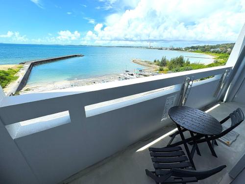 a balcony with two chairs and a view of the ocean at Crest Blue 404-オーシャンフロント! 新築マンション! in Kin