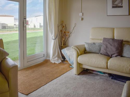 a living room with a couch and a sliding glass door at Mr Seal - Uk41452 in Hunstanton
