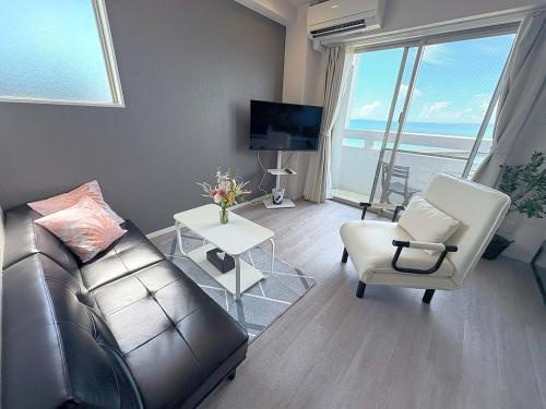 a living room with a couch and chairs and a television at Crest Blue 404-オーシャンフロント! 新築マンション! in Kin