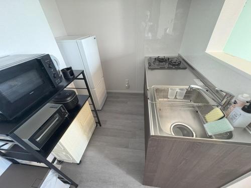 a small kitchen with a sink and a refrigerator at Crest Blue 404-オーシャンフロント! 新築マンション! in Kin