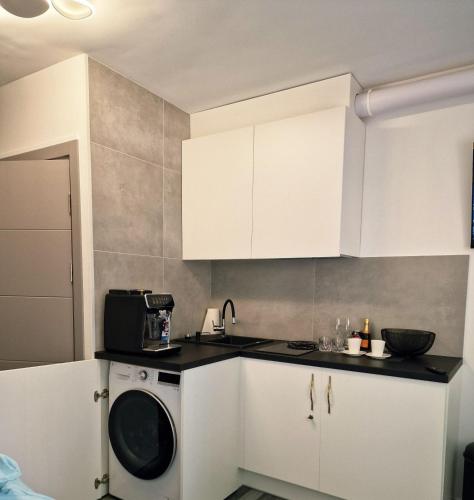 a kitchen with white cabinets and a washing machine at RentA Citywalk Flat in Kaunas