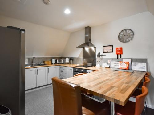 a kitchen with a wooden table and a clock on the wall at Ptarmigan Lodge in Balmaha