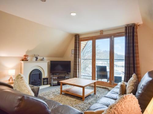 a living room with a couch and a table at Ptarmigan Lodge in Balmaha