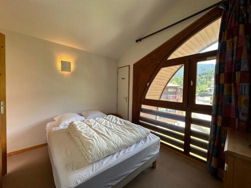 une chambre avec un lit et une grande fenêtre dans l'établissement Duplex 2 étoiles aux pieds des pistes avec balcon, parking et équipement complet - FR-1-642-19, à Morillon