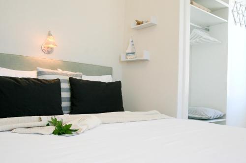 a bedroom with a white bed with black pillows at Paradissos Hotel in Pera Gyalos