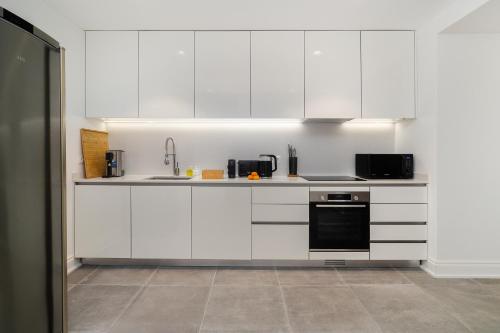 a kitchen with white cabinets and a black appliance at WHome Stylish Oasis near Parque Eduardo VII in Lisbon