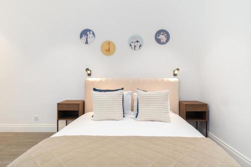 a bedroom with a bed with pillows and clocks on the wall at WHome Stylish Oasis near Parque Eduardo VII in Lisbon