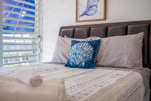 a bed with blue and white pillows and a window at Dorado Del Mar Villa by PH in Dorado