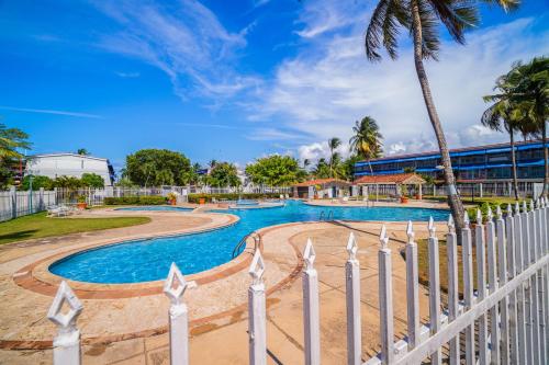 a swimming pool with a fence and palm trees at Dorado Del Mar Villa by PH in Dorado
