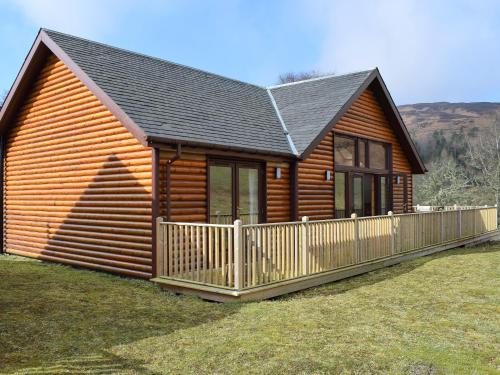 a log cabin with a wooden fence in the grass at Frith View in White Bridge